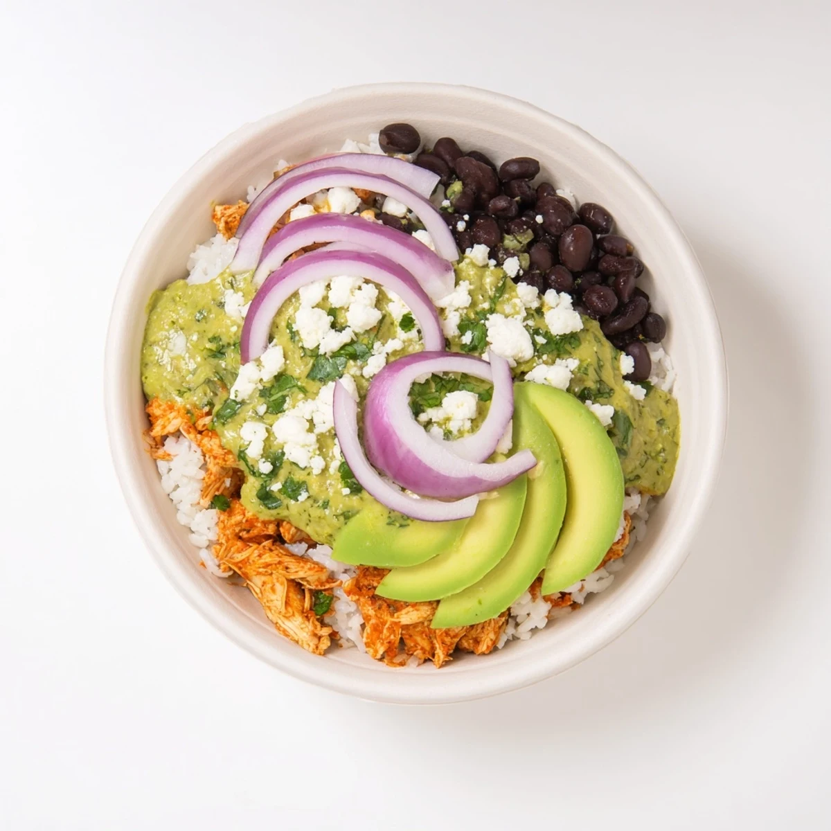 A close-up of a loaded Green Enchilada Rice Bowl, featuring creamy avocado and a squeeze of lime juice for flavor.