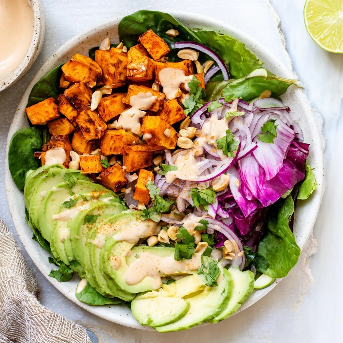 Warm, roasted sweet potatoes and a zesty peanut dressing star in this vibrant salad bowl.