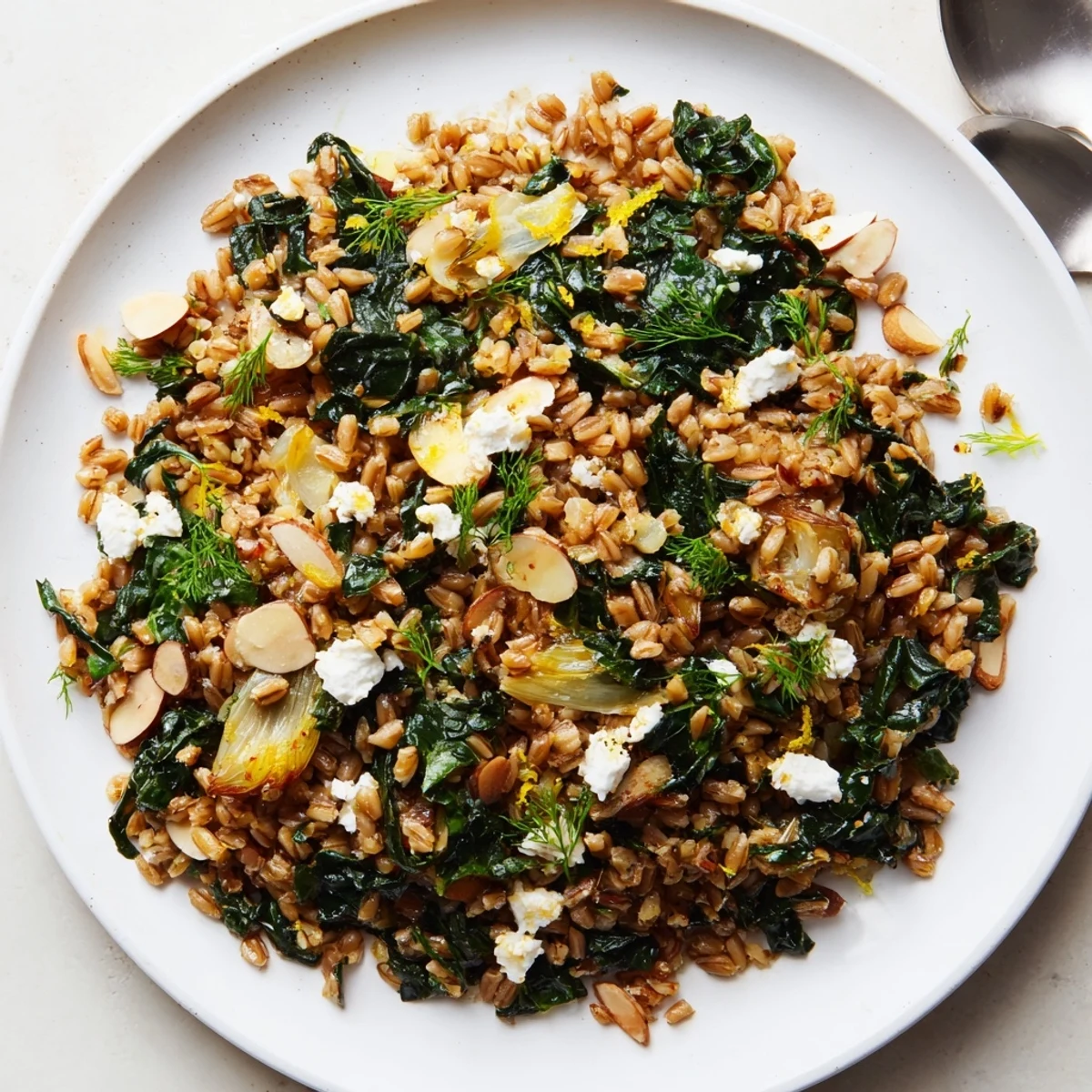 Steaming bowl of warm Farro & Greens Pilaf, topped with toasted almonds and fresh parsley.