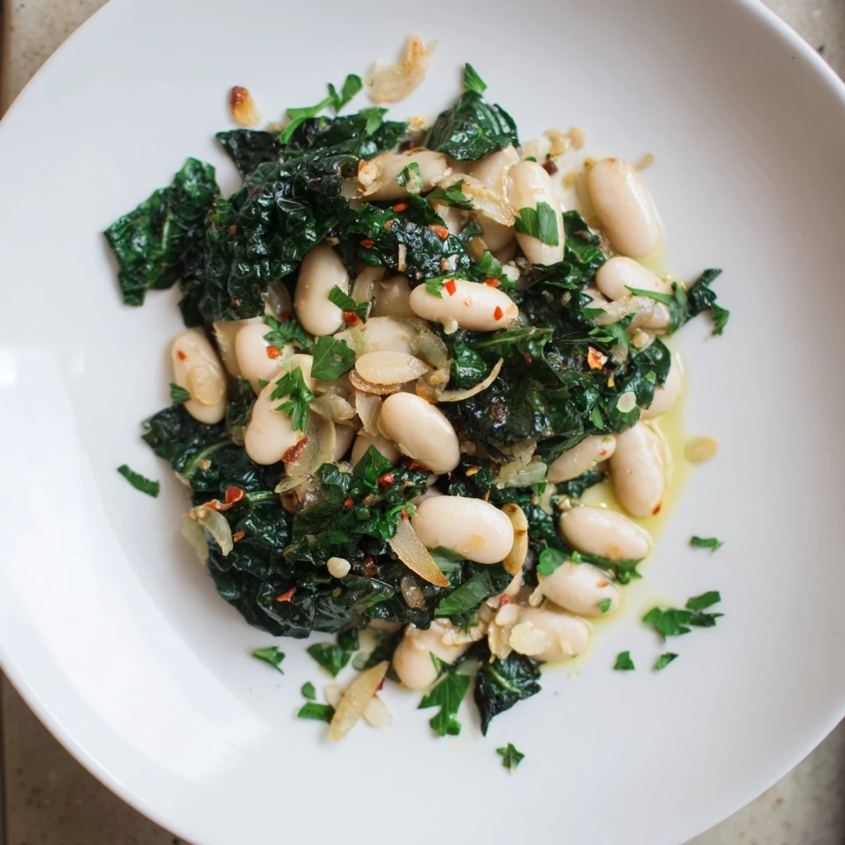 Steaming bowl of Garlicky Beans with Winter Greens, featuring vibrant greens and creamy white beans.
