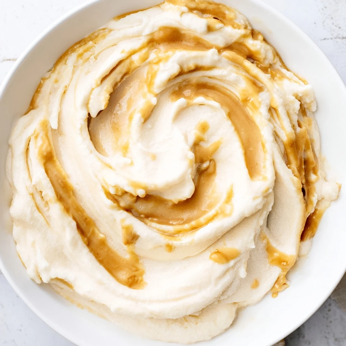Creamy peanut butter banana ice cream with visible flecks of peanut butter in a dairy-free dessert.