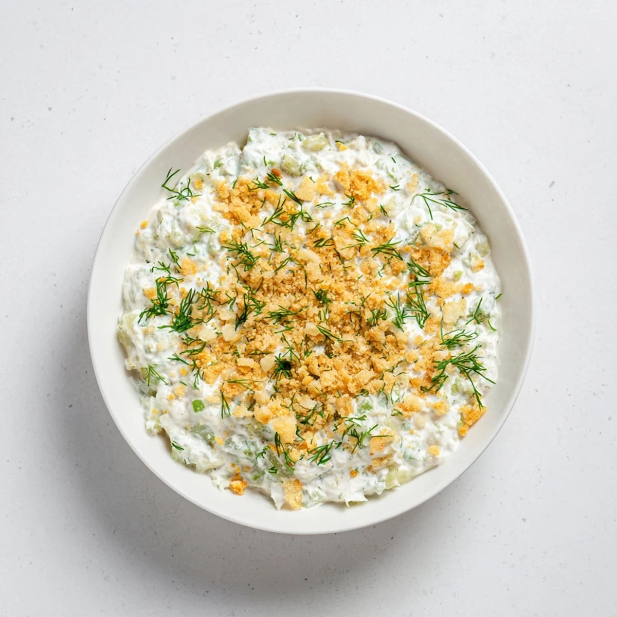 Creamy fried pickle dip, garnished with fresh dill, served with crispy potato chips for dipping.