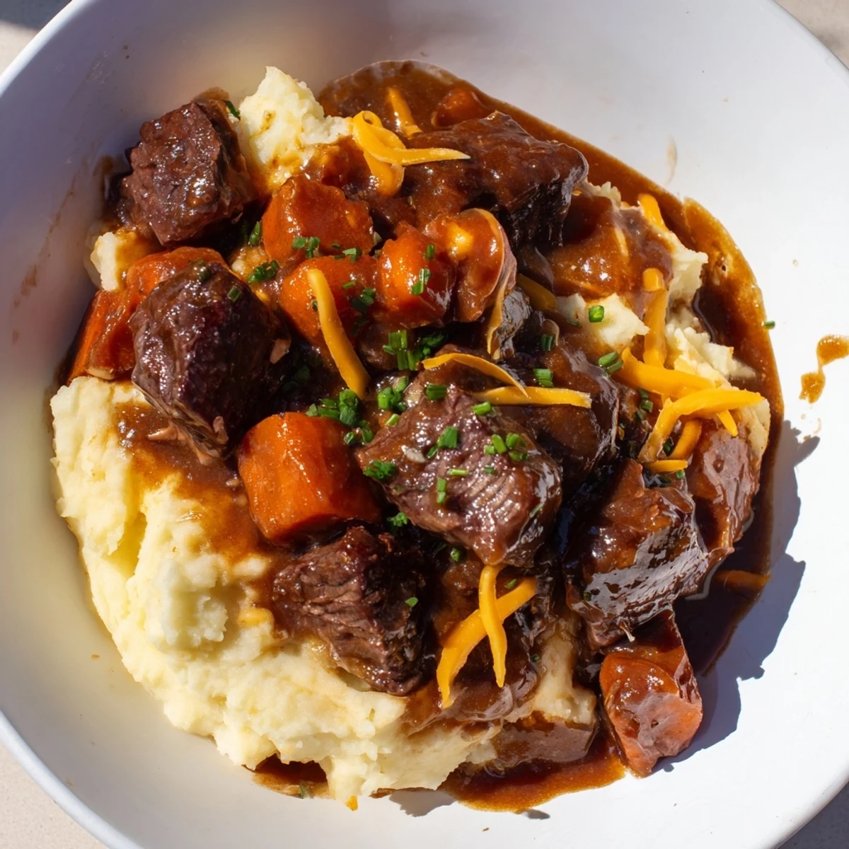 Golden-brown Fall Apple Cider Stew ladled over creamy cheddar mashed potatoes, a warm dinner.