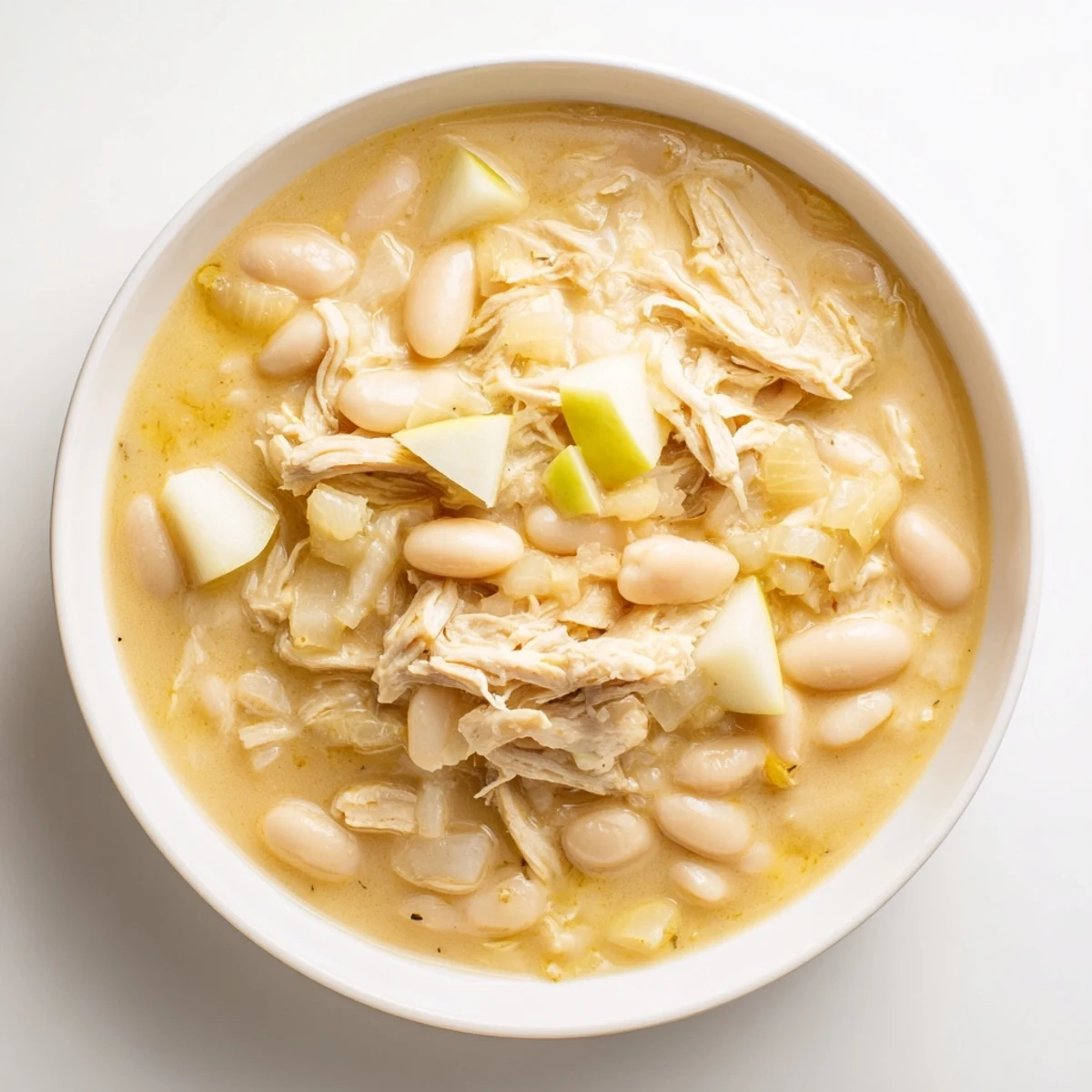 Steaming bowl of 35-Minute White Cheddar Apple Chicken Chili, featuring melted cheese and diced apples.
