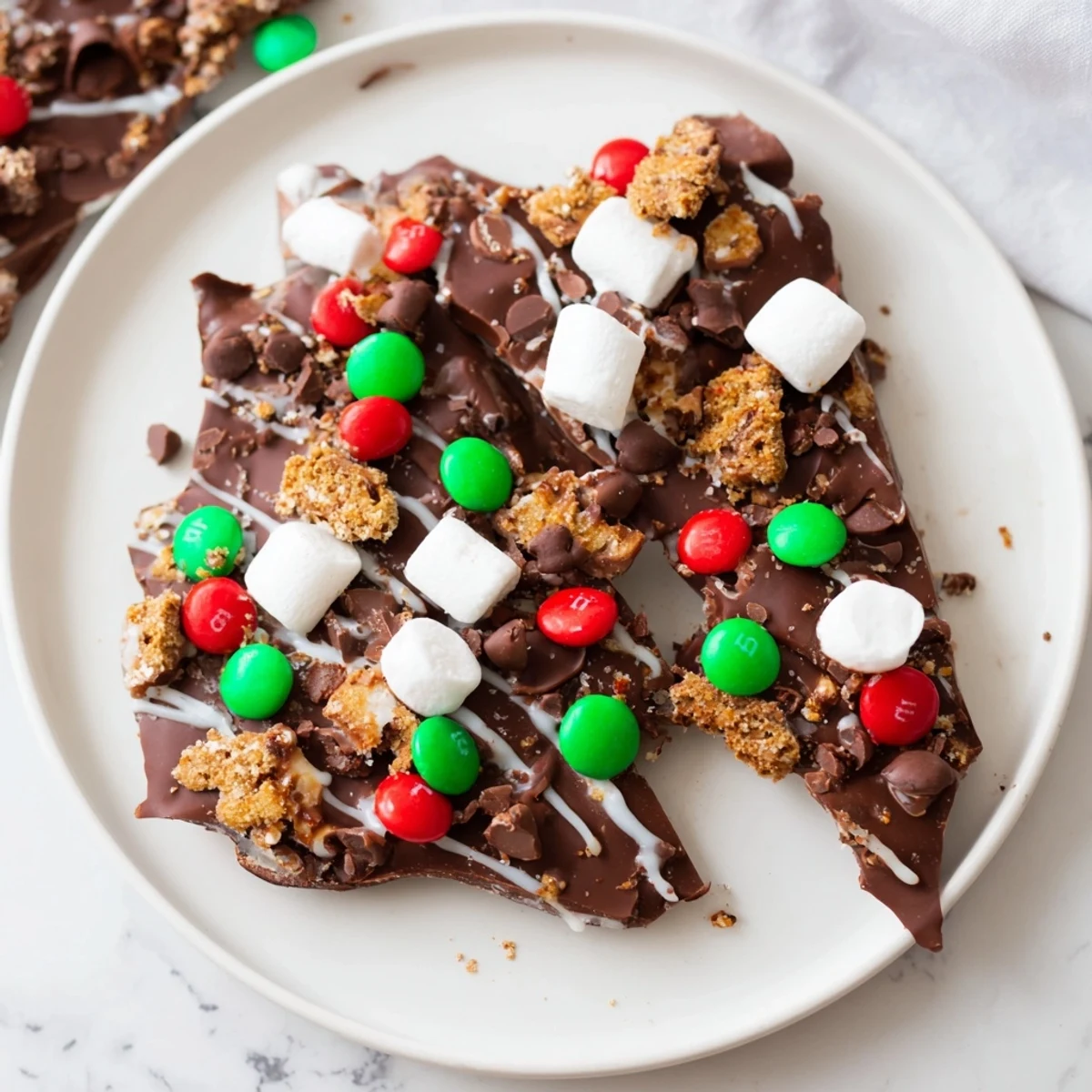 Quick Christmas Smores Bark: A close-up of festive, chocolatey pieces loaded with graham crackers and marshmallows.