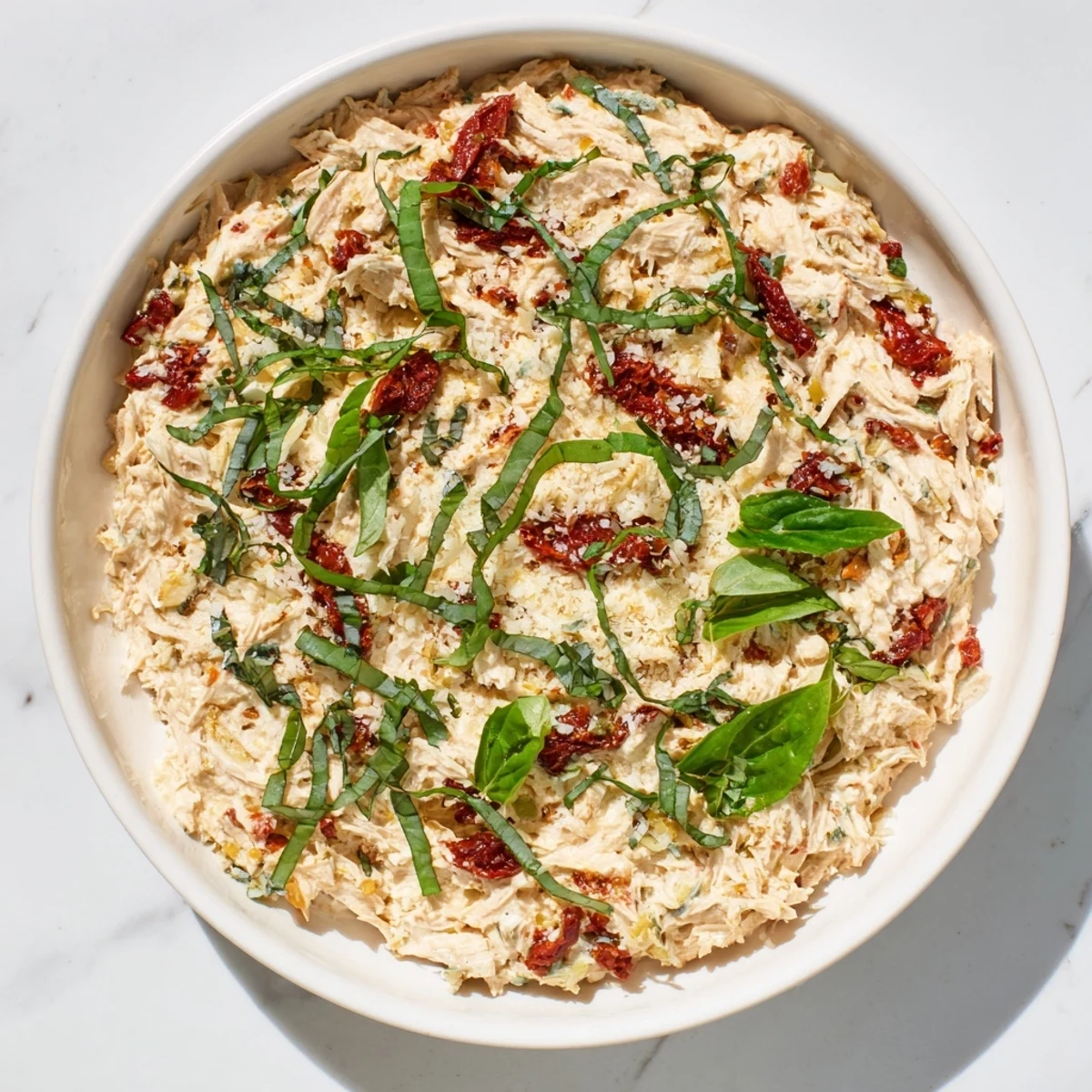 The flavorful, loaded Lightened Marry Me Chicken Dip is being scooped up with crispy crackers, ready to enjoy.