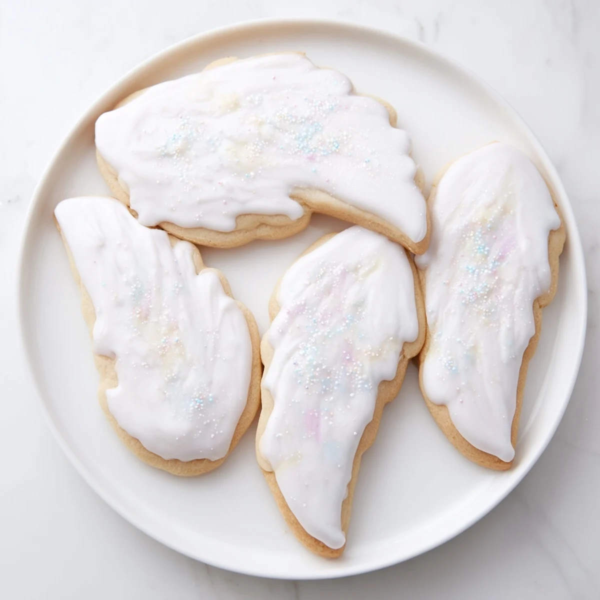 Plate of golden-baked Angel Wings sugar cookies, iced and sparkling, ready to enjoy.
