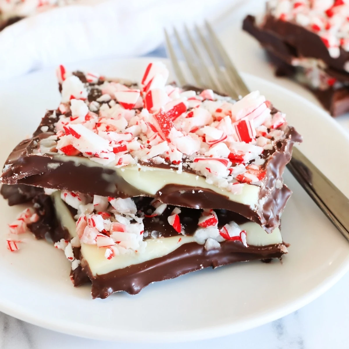 Close-up of shimmering Peppermint Bark Snowflakes: layers of chocolate topped with crushed peppermint.