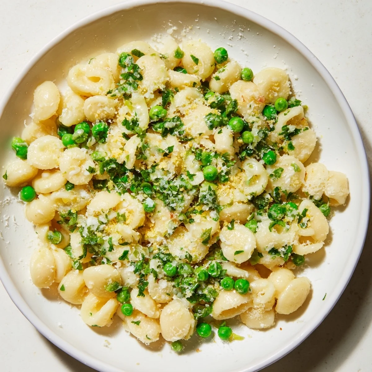 A steaming bowl of garlic butter ditalini, the peas adding a fresh, vibrant pop of color.