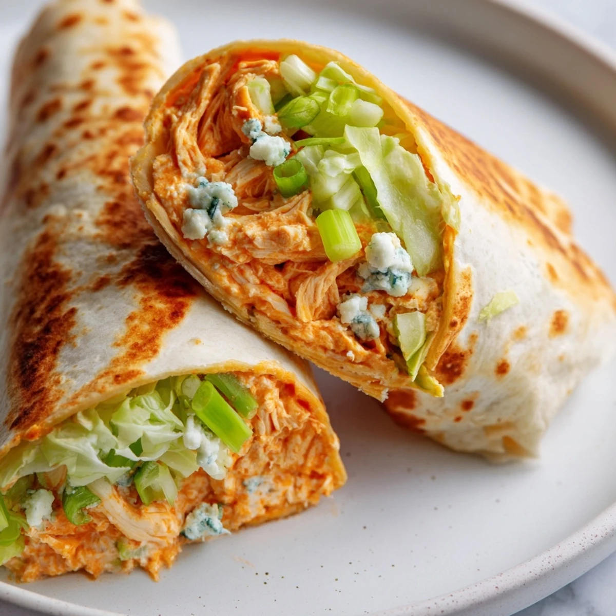 Close-up of a perfectly rolled Buffalo Chicken Dip Wrap, showcasing a creamy, cheesy, and spicy filling.