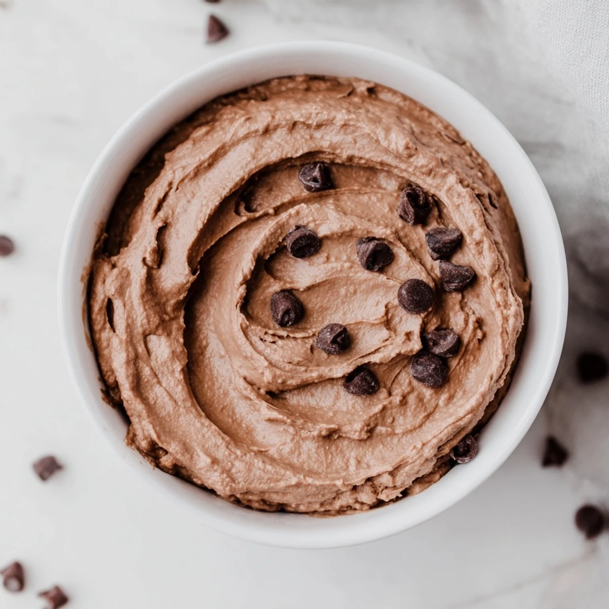 A bowl of rich, dark Chocolate Hummus ready to be scooped up with fresh fruit.