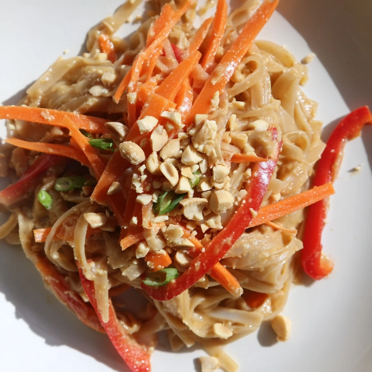 Steaming Spicy Peanut Noodles with vibrant vegetables and peanuts, ready for a delicious, quick dinner.