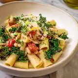 Vibrant image shows Healthy Tuscan White Bean & Kale Christmas Pasta with fresh kale and Parmesan cheese, ready to serve.