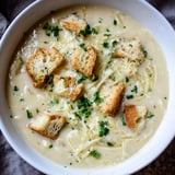 This close-up of Creamy Garlic Bread Soup features the creamy broth garnished with fresh parsley.