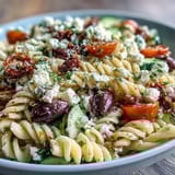 Greek pasta salad with fresh vegetables, olives, and feta, perfect for picnics.