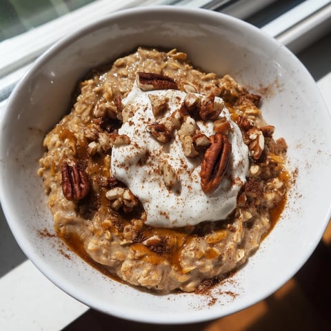 Steaming bowl of Pumpkin Spice Latte Oats, topped with whipped cream and chopped pecans.