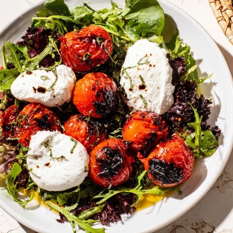Plump, charred cherry tomatoes atop greens with creamy burrata, a lovely Charred Tomato Salad.