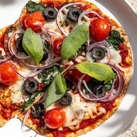 Golden, crispy tortilla pizza with melted cheese and fresh basil, ready to slice.