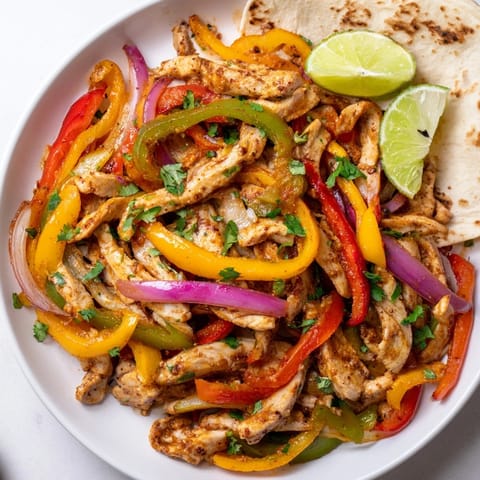 Savory sheet pan chicken fajitas with roasted peppers and warm tortilla wraps.  