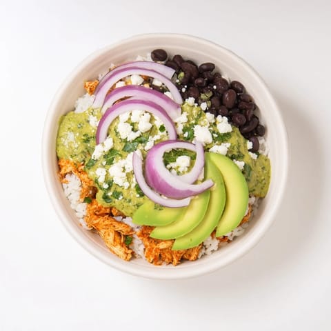 A close-up of a loaded Green Enchilada Rice Bowl, featuring creamy avocado and a squeeze of lime juice for flavor.