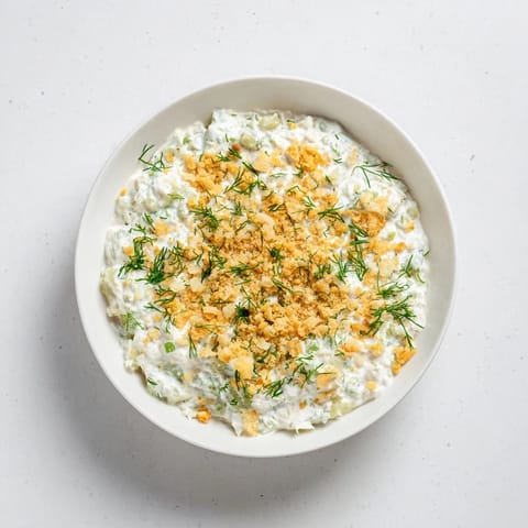 Creamy fried pickle dip, garnished with fresh dill, served with crispy potato chips for dipping.