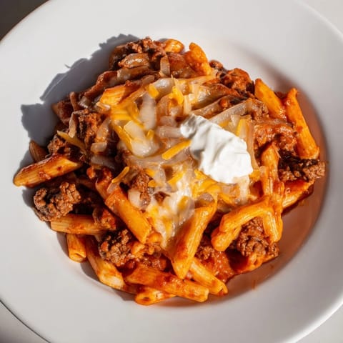 Savory Easy Beef Enchilada Pasta, garnished with cheese and sour cream: a comforting dinner idea.