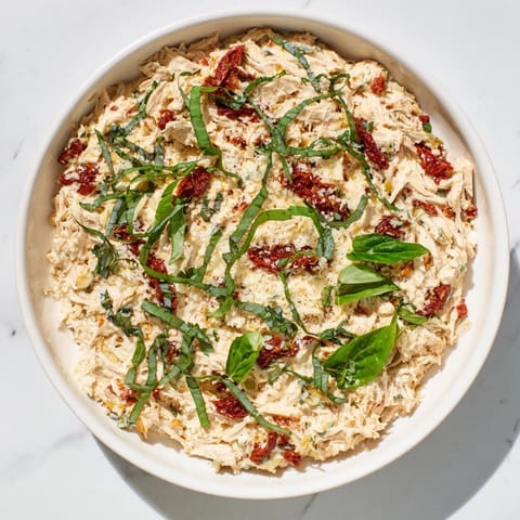 The flavorful, loaded Lightened Marry Me Chicken Dip is being scooped up with crispy crackers, ready to enjoy.