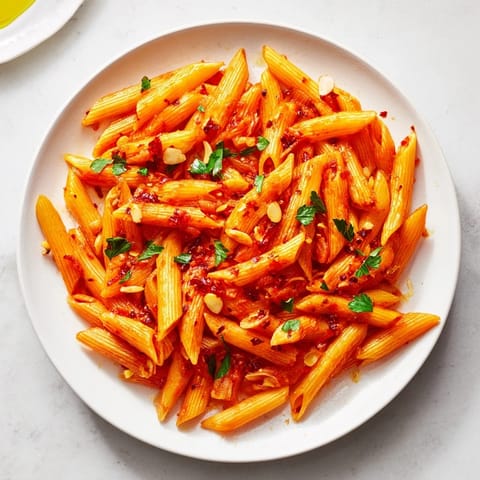 Vibrant penne all'arrabbiata: perfectly cooked pasta coated in a spicy tomato and garlic sauce.