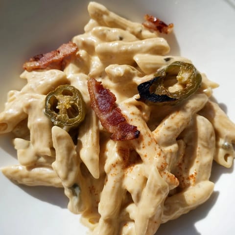 Roasted jalapeños and gooey cheese sauce coat penne pasta, creating a spicy, decadent comfort food meal ready for dinner.