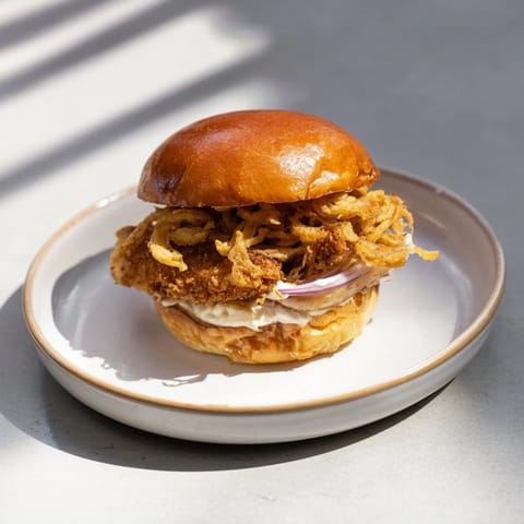 Succulent Crispy Onion Chicken Sandwich with buttermilk-fried chicken, crunchy onions, and fresh lettuce leaves.