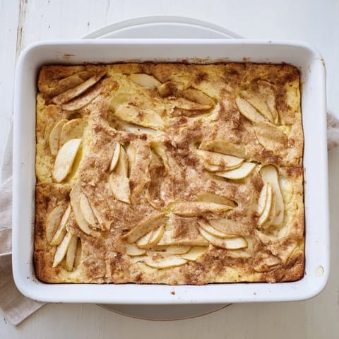 A slice of homemade Dutch-inspired Baked Apple Cake with tender apple slices and a soft, spiced crumb on a plate.