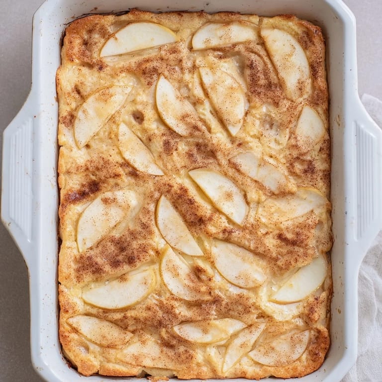 Cozy breakfast Baked Apple Cake with sliced apples and cinnamon, ready to serve with a dollop of crème fraîche.