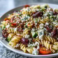Vibrant summer pasta salad, Greek style, bursting with feta and olives.