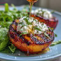 Creamy burrata and sweet grilled peaches mingle atop fresh greens in this salad.